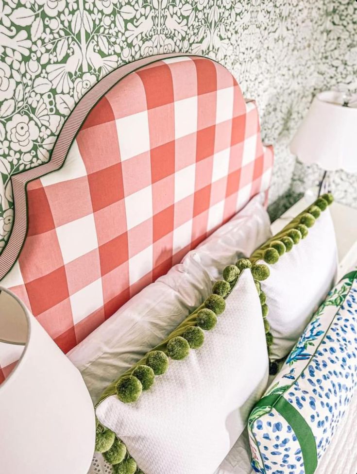 a bed with many pillows on top of it and a checkered headboard in the background