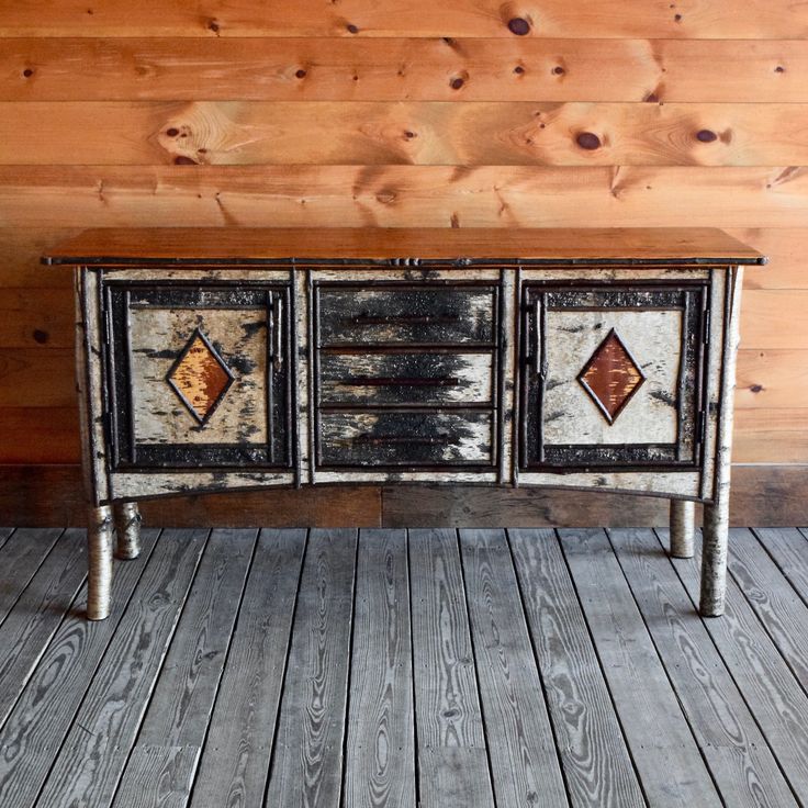 an old dresser is painted black and white with brown diamond designs on the doors, along with wood flooring