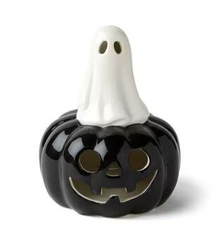 a black and white ceramic pumpkin with a ghost face on it's head, sitting in front of a white background