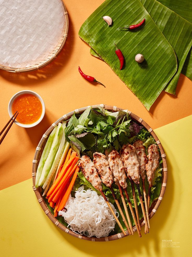 a plate with meat, rice and veggies on it next to some chopsticks