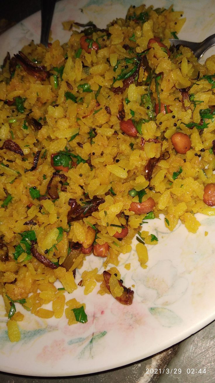 a white plate topped with rice covered in nuts and veggies next to a fork