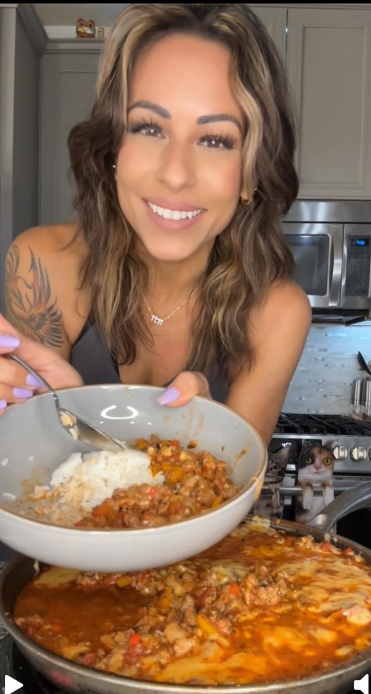 a woman is smiling while holding a bowl of food