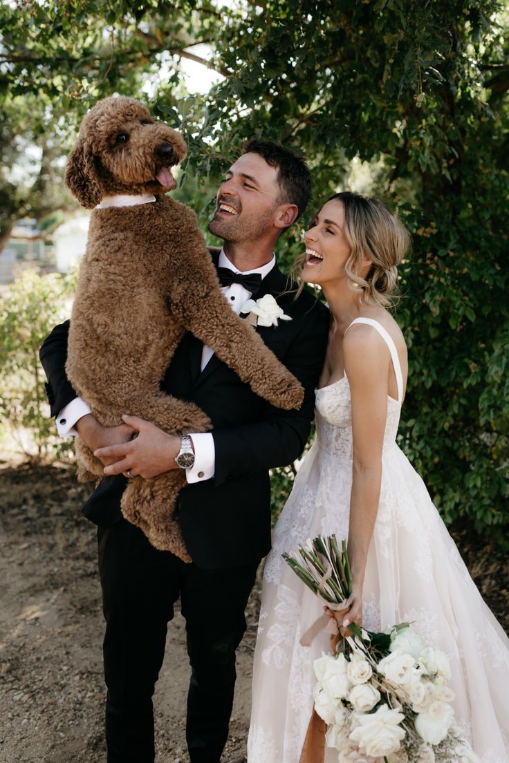 a man in a tuxedo holding a teddy bear next to a woman in a wedding dress