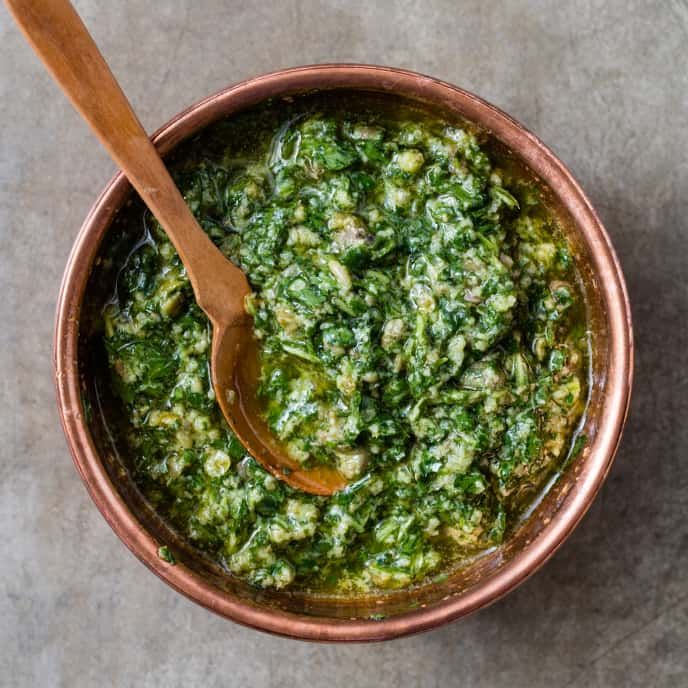 a wooden spoon in a metal bowl filled with pesto