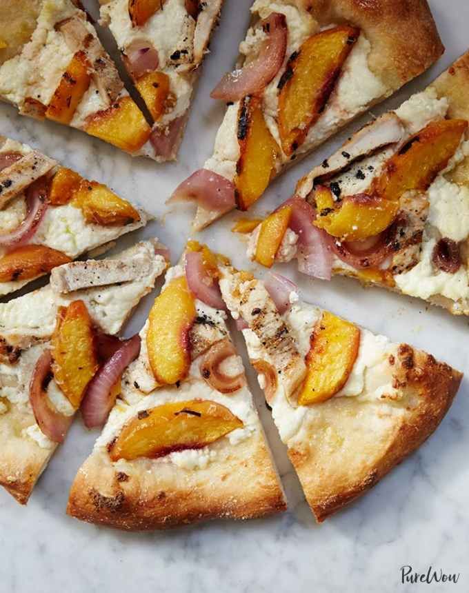 a pizza with peaches, chicken and cheese cut into slices on a white plate