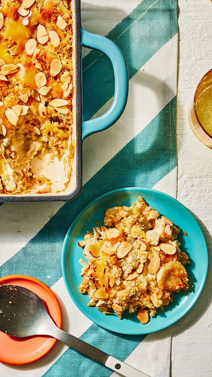 a blue plate topped with food next to a bowl of fruit and a pan of bread