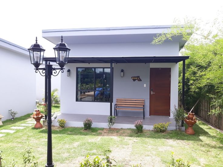 a small white house with a wooden bench in the front yard and lampposts