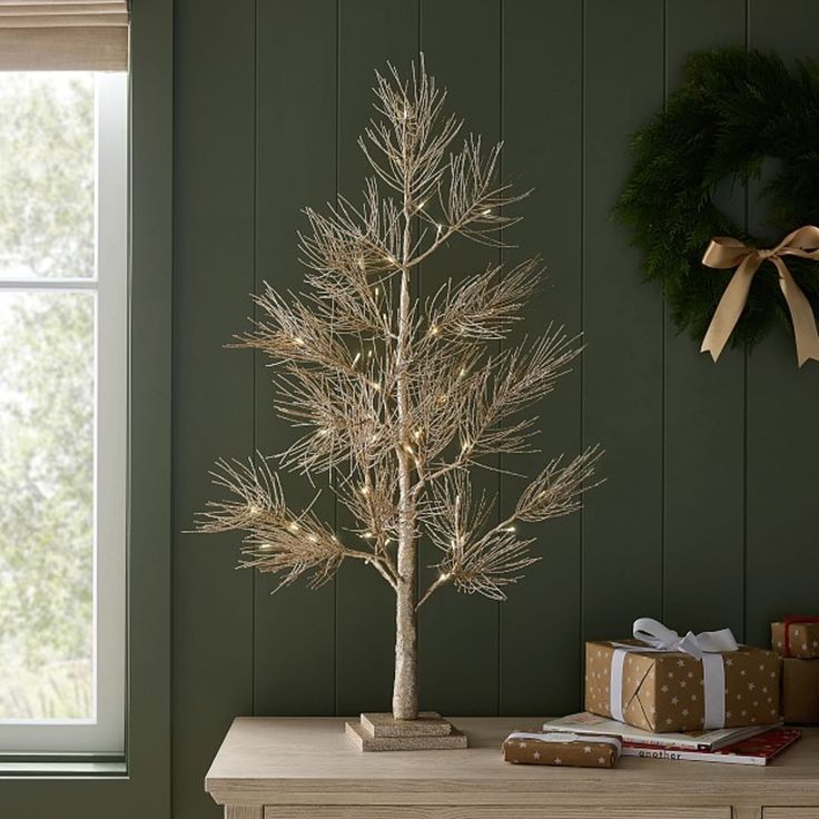 a small christmas tree sitting on top of a wooden table next to a present box