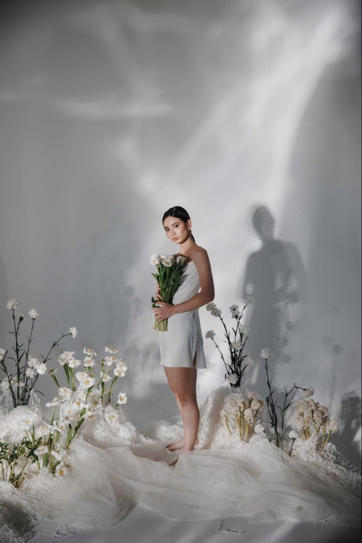 a woman in a white dress holding flowers