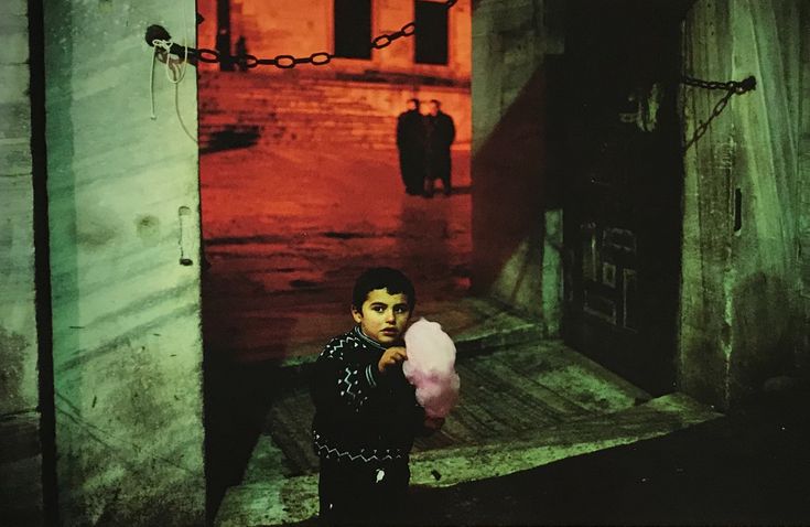 a young boy holding a pink ball in an alley