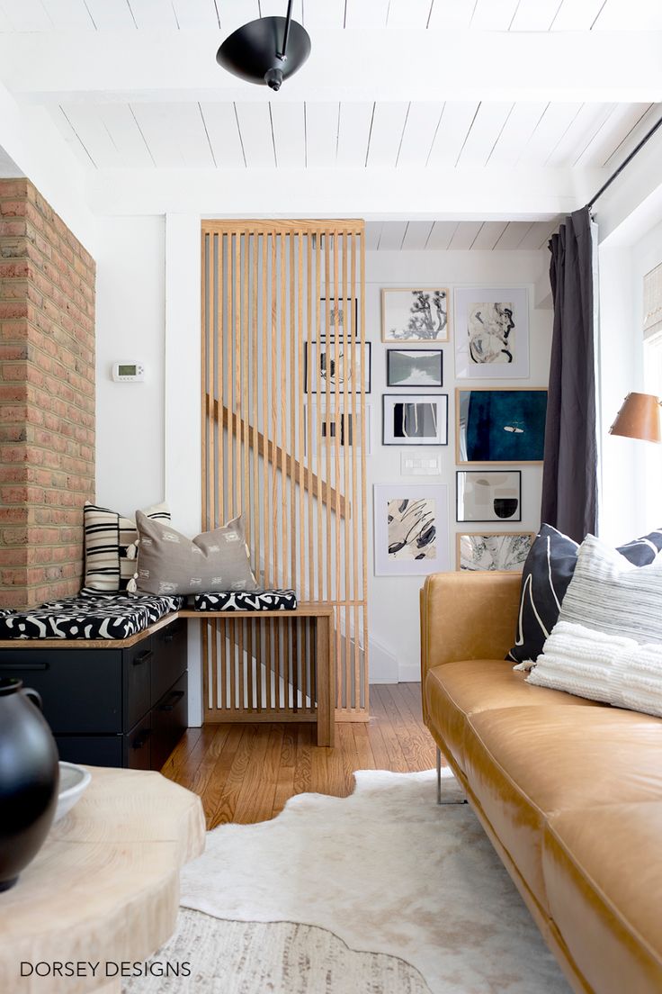 a living room filled with furniture next to a brick wall and wooden slatted walls