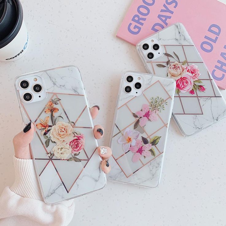 three phone cases with flowers on them sitting next to a coffee cup and a book