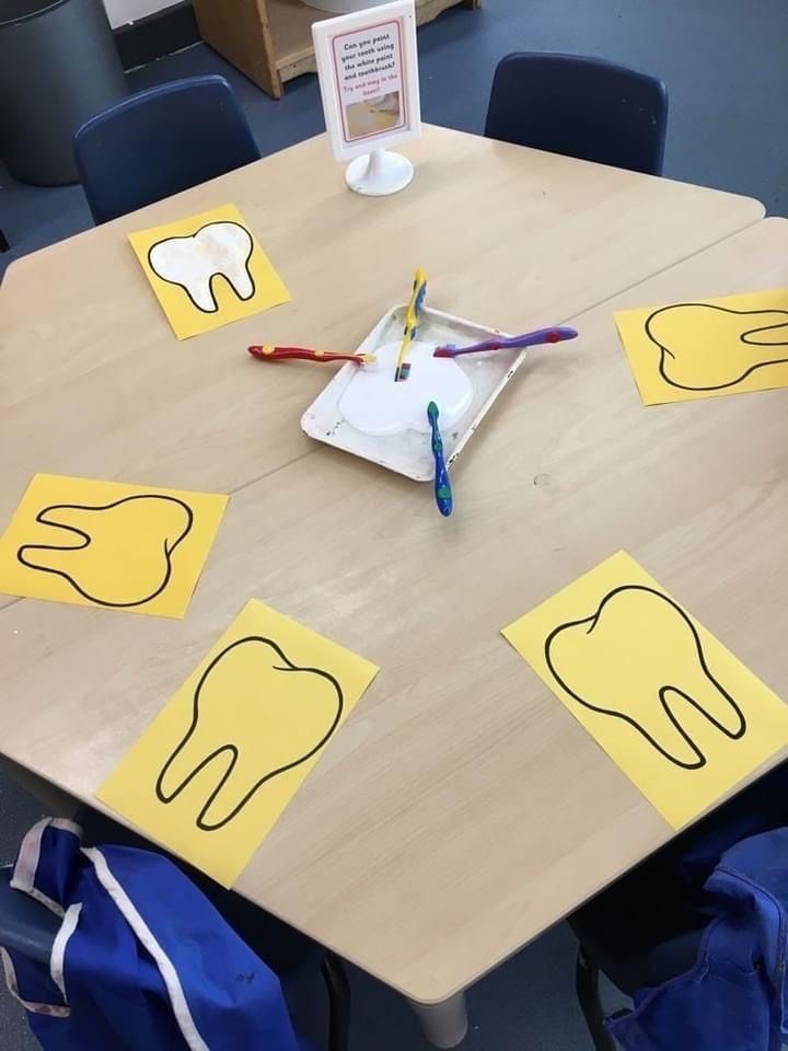 a wooden table topped with paper cut out of the shape of teeth and toothbrushes