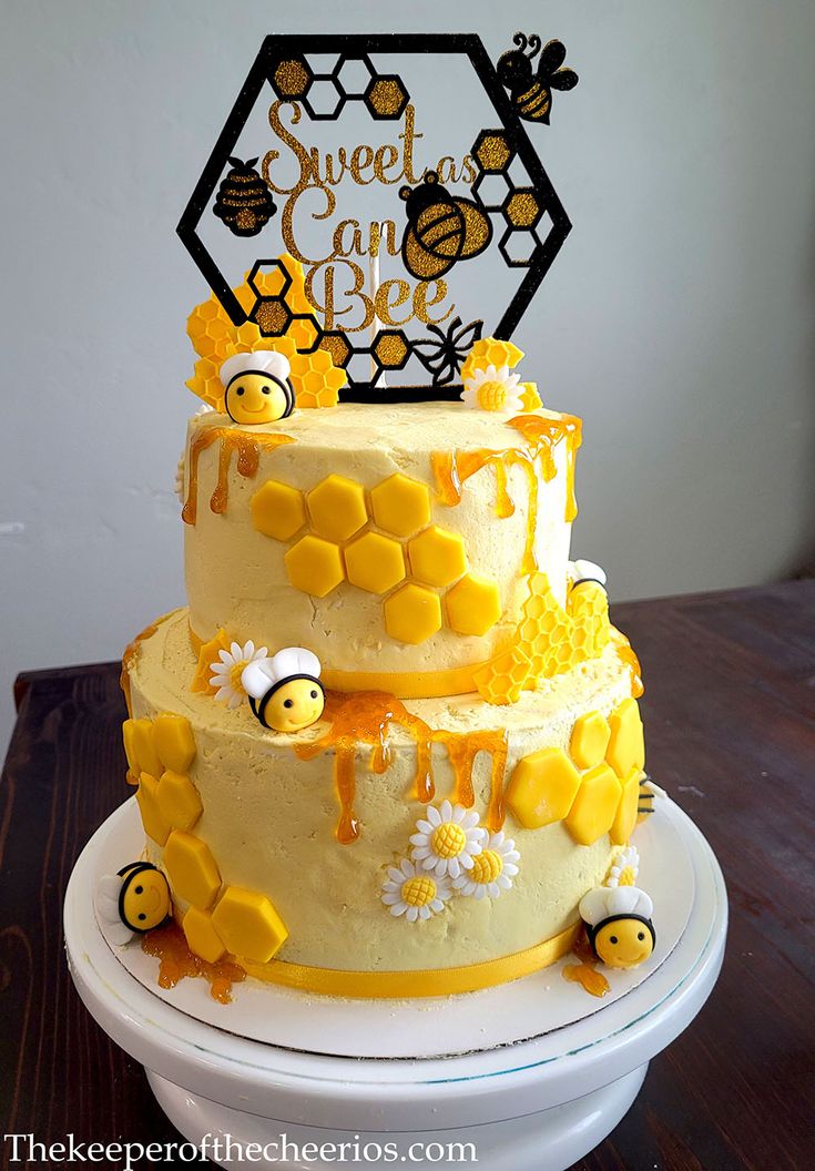 a three tiered cake with bees and honeycombs on the top is decorated with a sign that says sweet as can bee