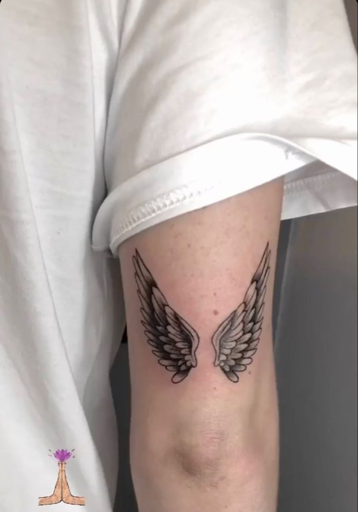 a person with a tattoo on their arm that has two black and white angel wings