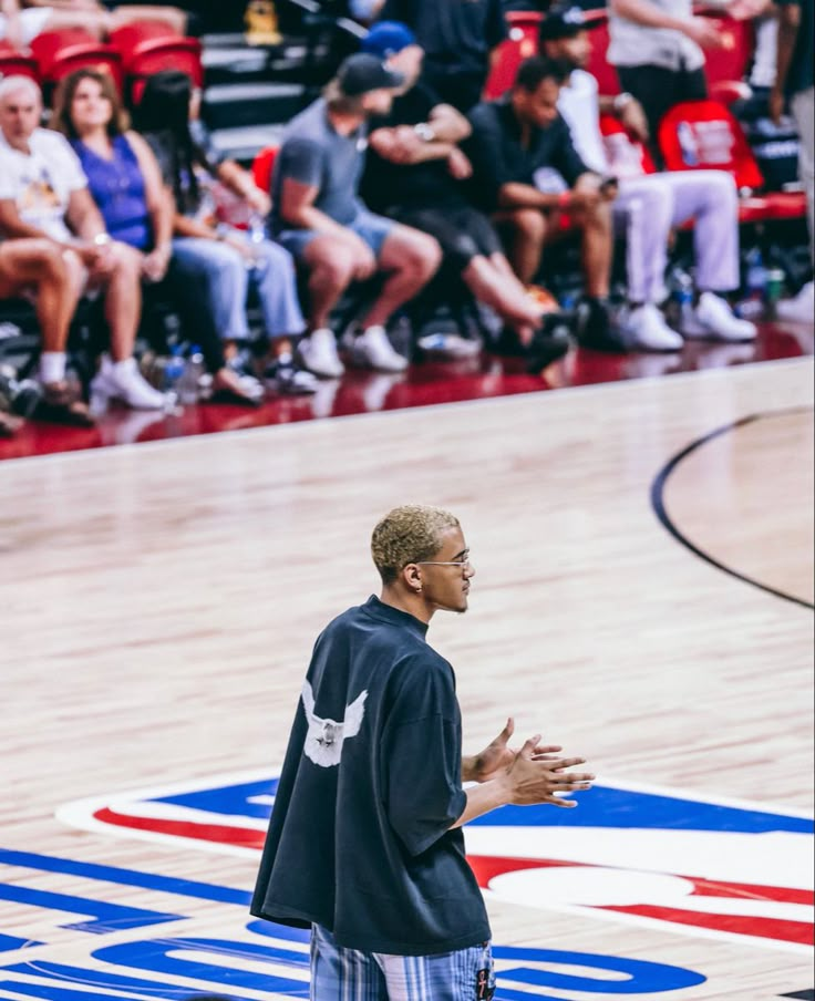 a man standing on top of a basketball court with his hands out in front of him