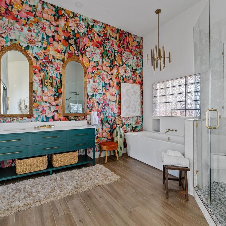 a bathroom with floral wallpaper and wooden floors, including a large mirror on the wall