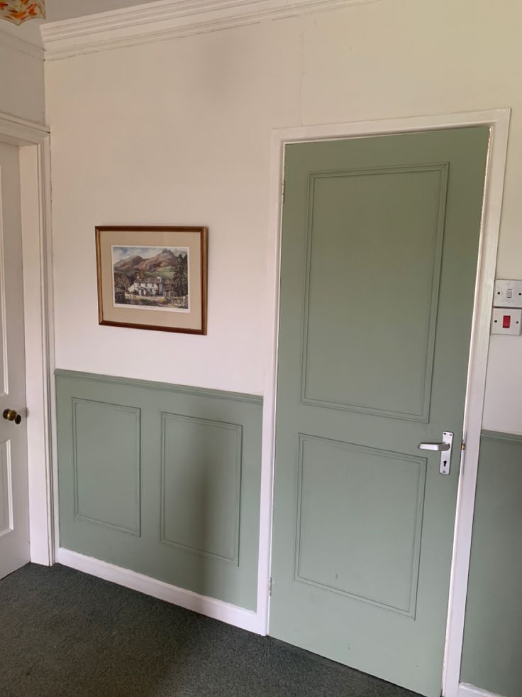 a room with two green doors and a framed picture on the wall above one door