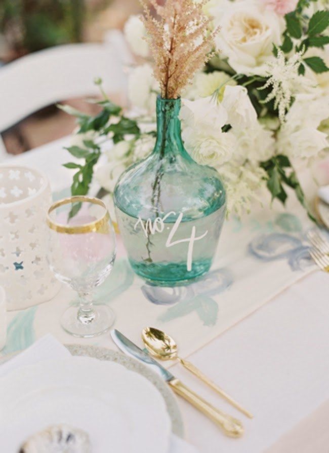 the table is set with white flowers and silverware, including a vase filled with greenery