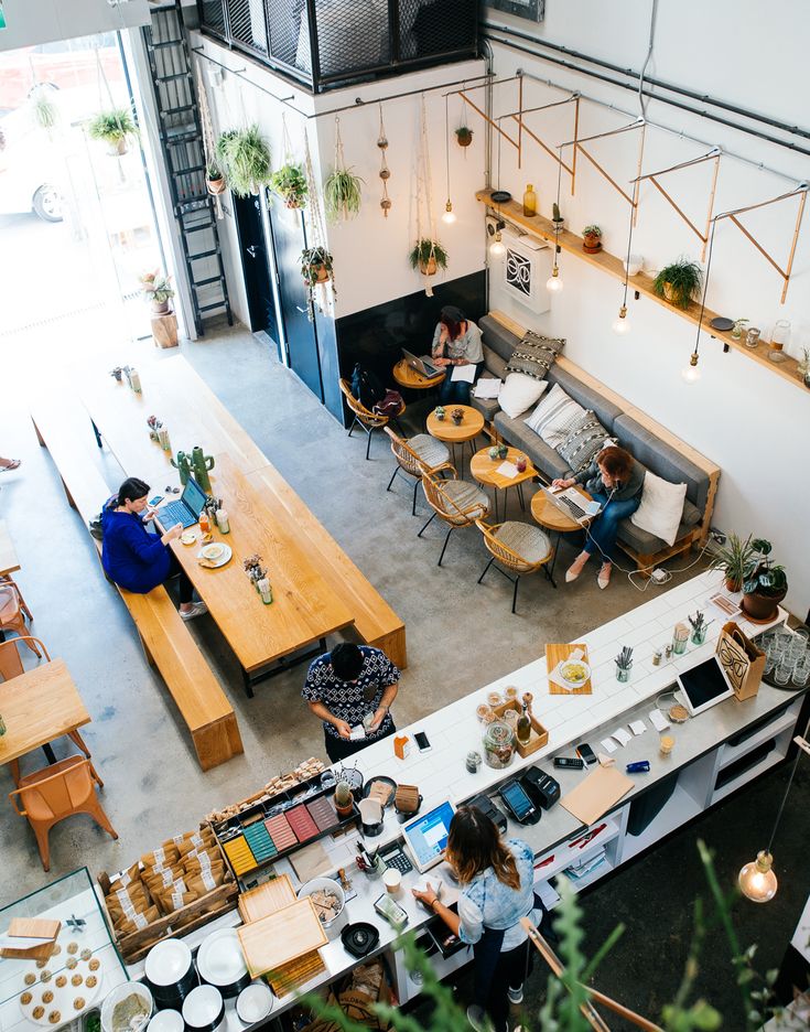 an overhead view of people sitting at tables in a coffee shop with plants and potted plants