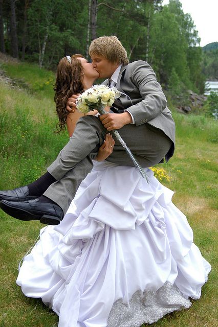 a bride and groom kissing in the grass