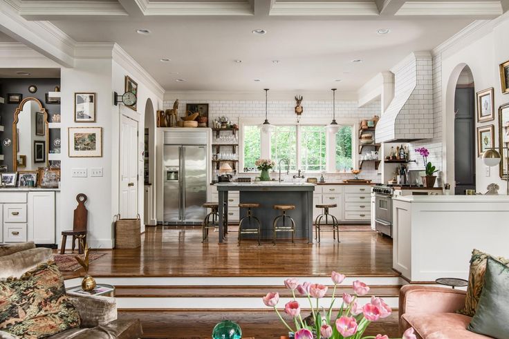 a large open kitchen and living room with hardwood floors, white walls, and wooden flooring