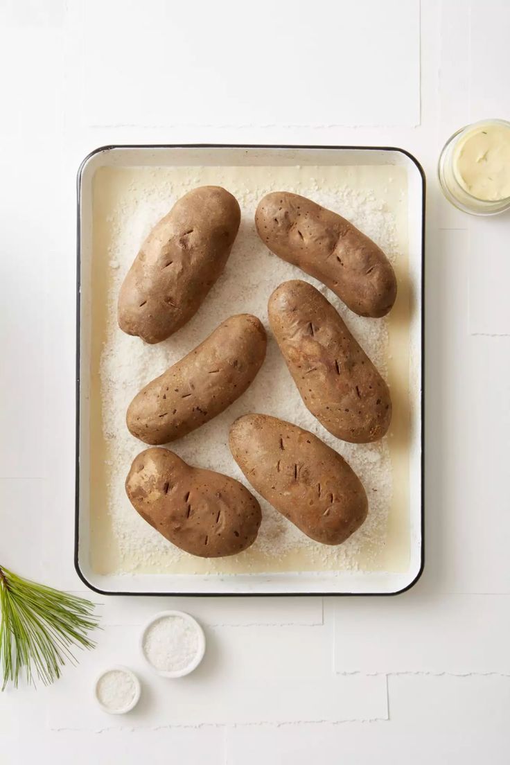 potatoes on a baking sheet with salt and butter in the background, next to a pine branch