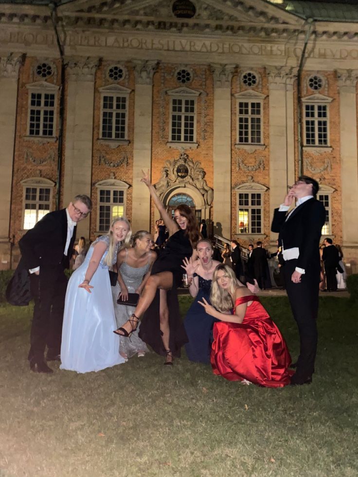 a group of people posing for a photo in front of a large building at night