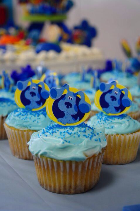 some cupcakes with blue frosting and yellow decorations on them are sitting on a table