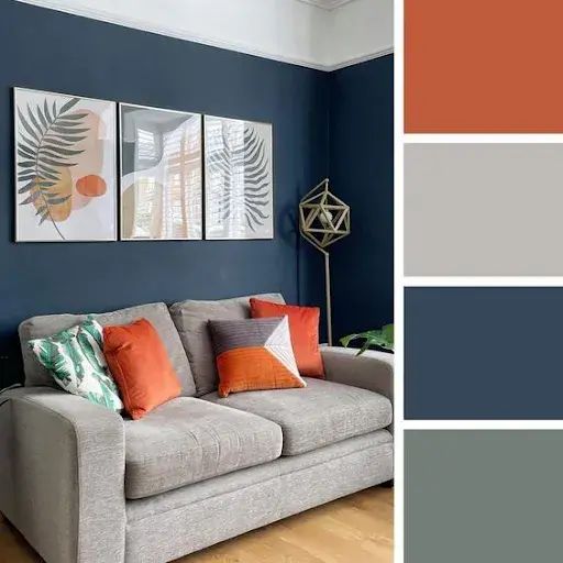 a living room with blue walls, orange and gray pillows on the couches in front of them