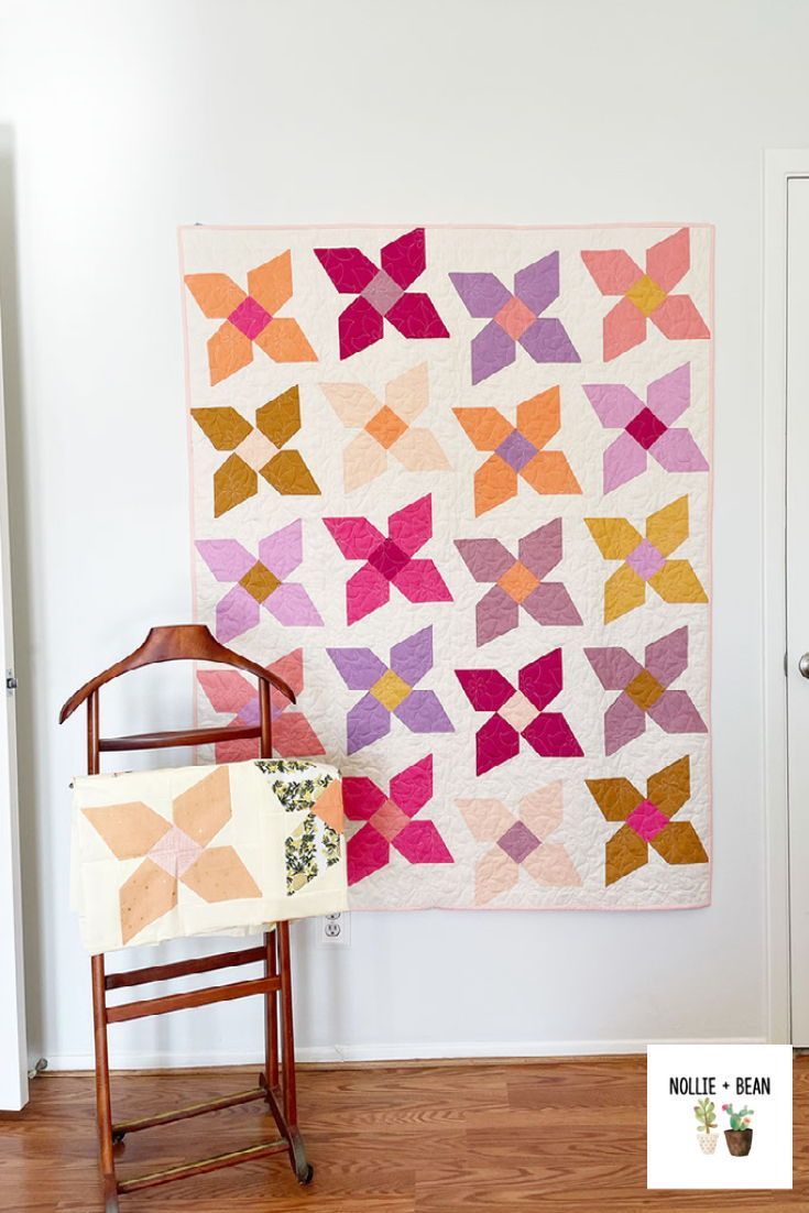 a wall hanging next to a chair with a quilt on it and an ironing board