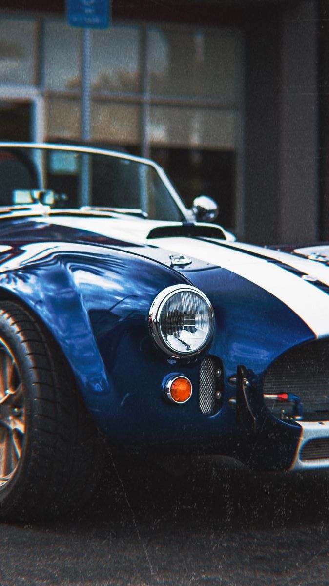 a blue and white sports car parked in front of a building