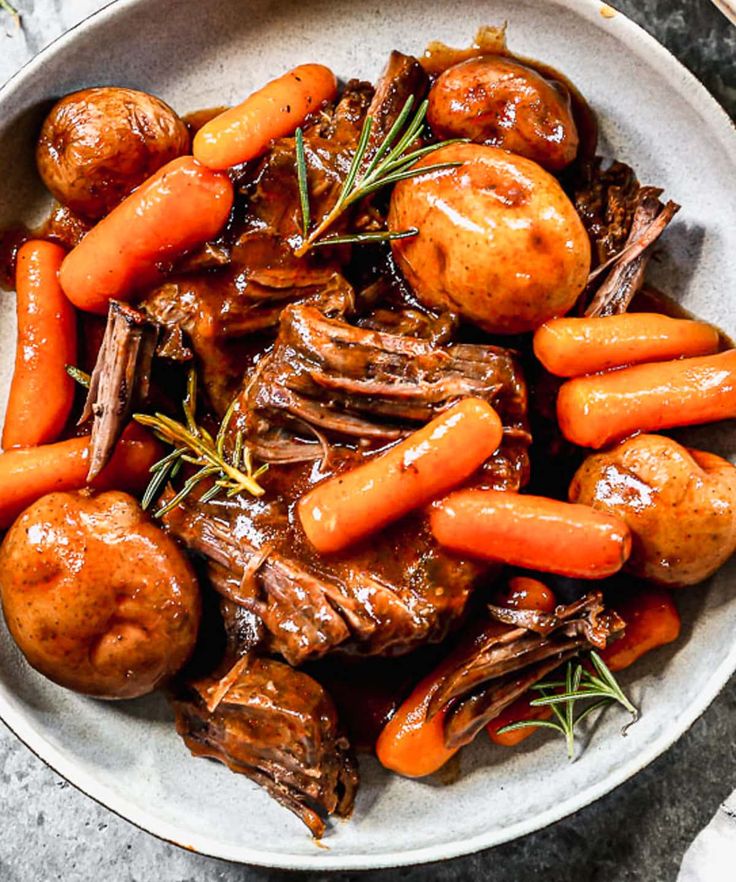 a bowl filled with meat and carrots covered in gravy on top of a table