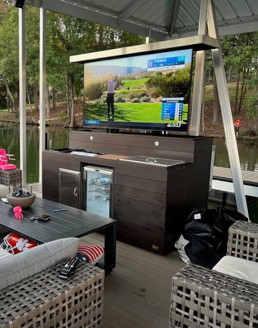 an outdoor living area with wicker furniture and a flat screen tv on the wall