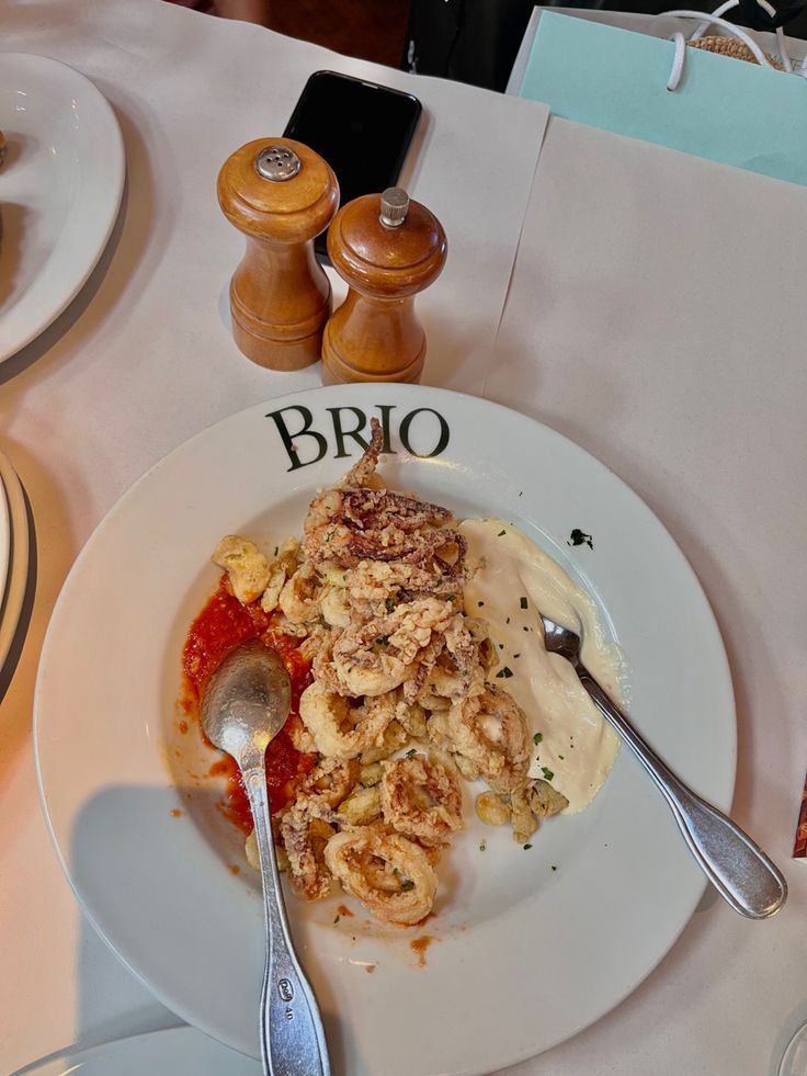 a white plate topped with food on top of a table next to two silver spoons