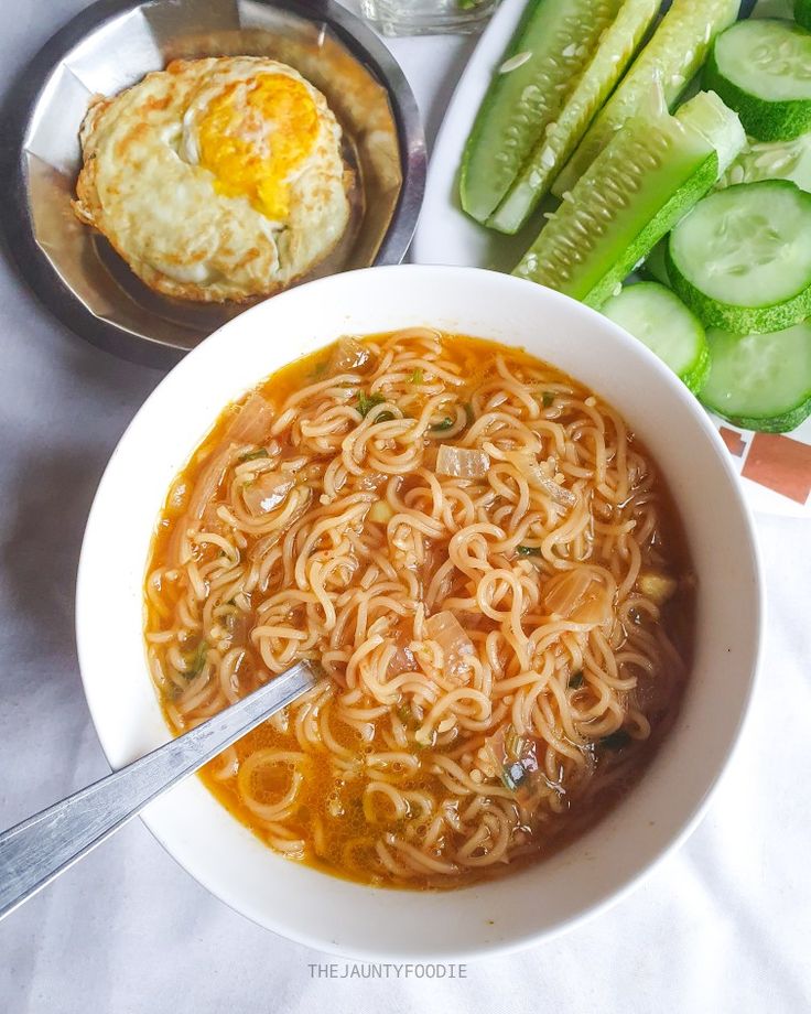 a bowl of noodles and cucumbers on a table