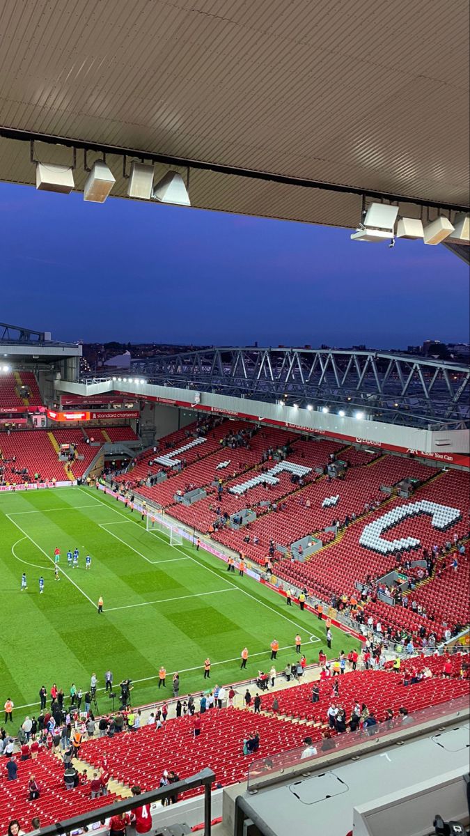 an empty stadium filled with lots of red seats and people standing on the sidelines