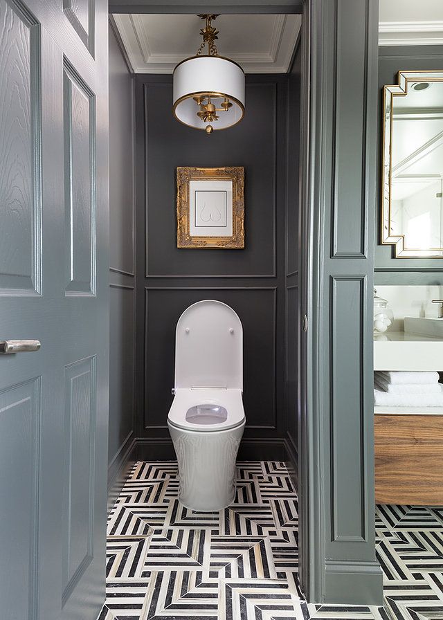 a toilet in a bathroom with gray walls and black and white floor tiles on the floor