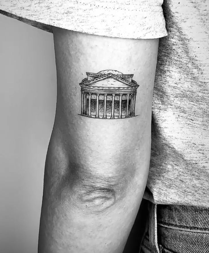 a black and white photo of a man's arm with a building tattoo on it