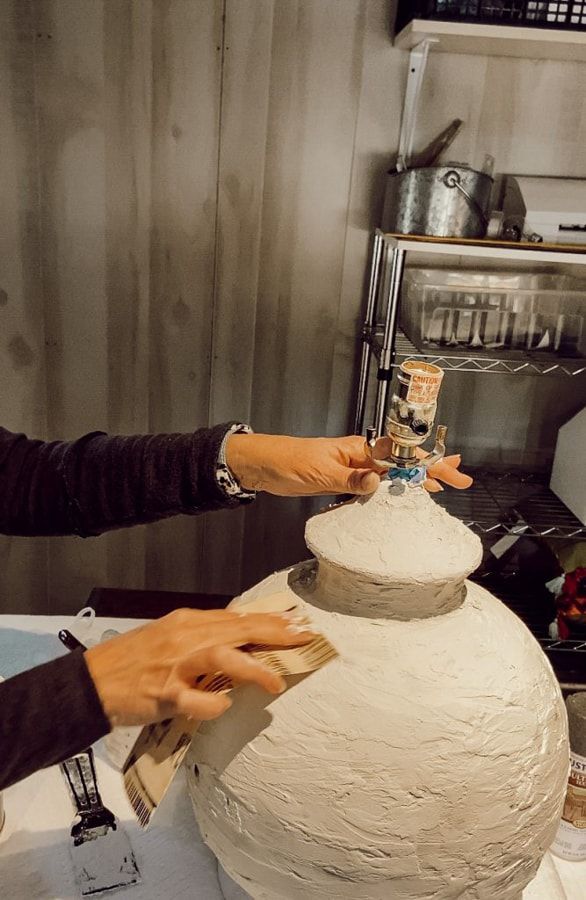 two people working on a clay sculpture in a kitchen