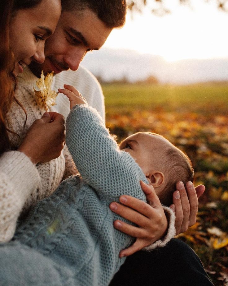 a man and woman holding a baby in their lap while they look at each other