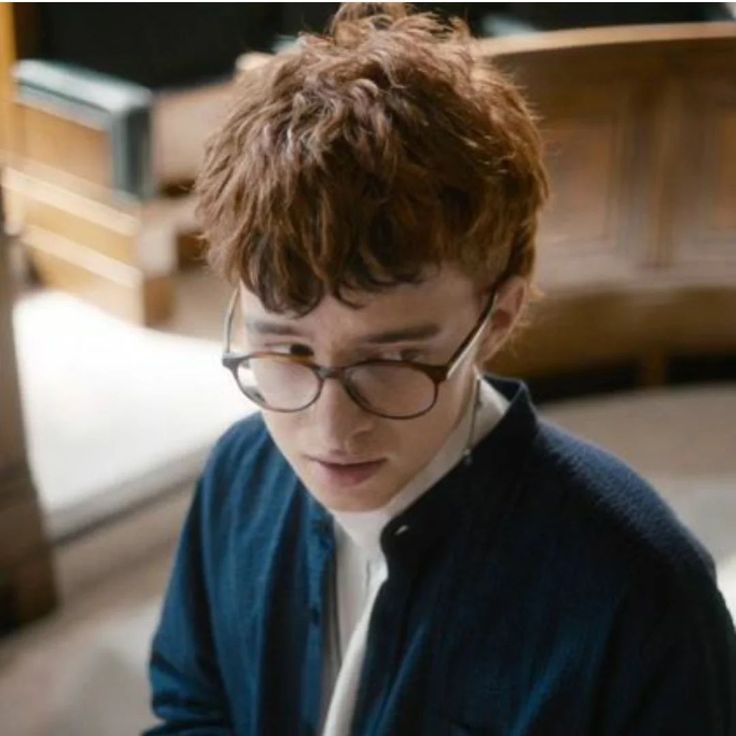 a young man wearing glasses looking at his cell phone