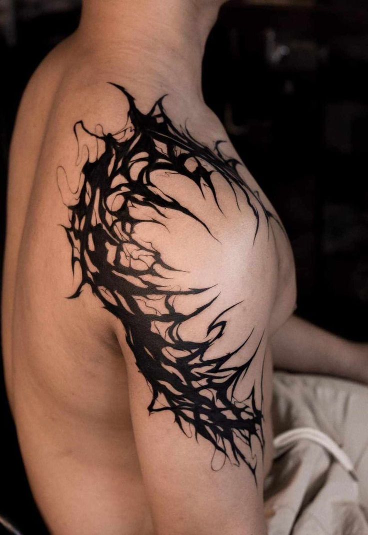 the back of a man's shoulder with an artistic tattoo design on his arm