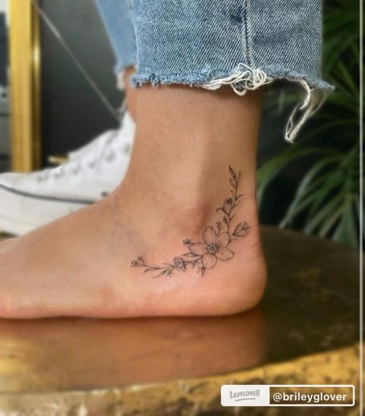 a woman's foot with a small flower tattoo on the side of her ankle