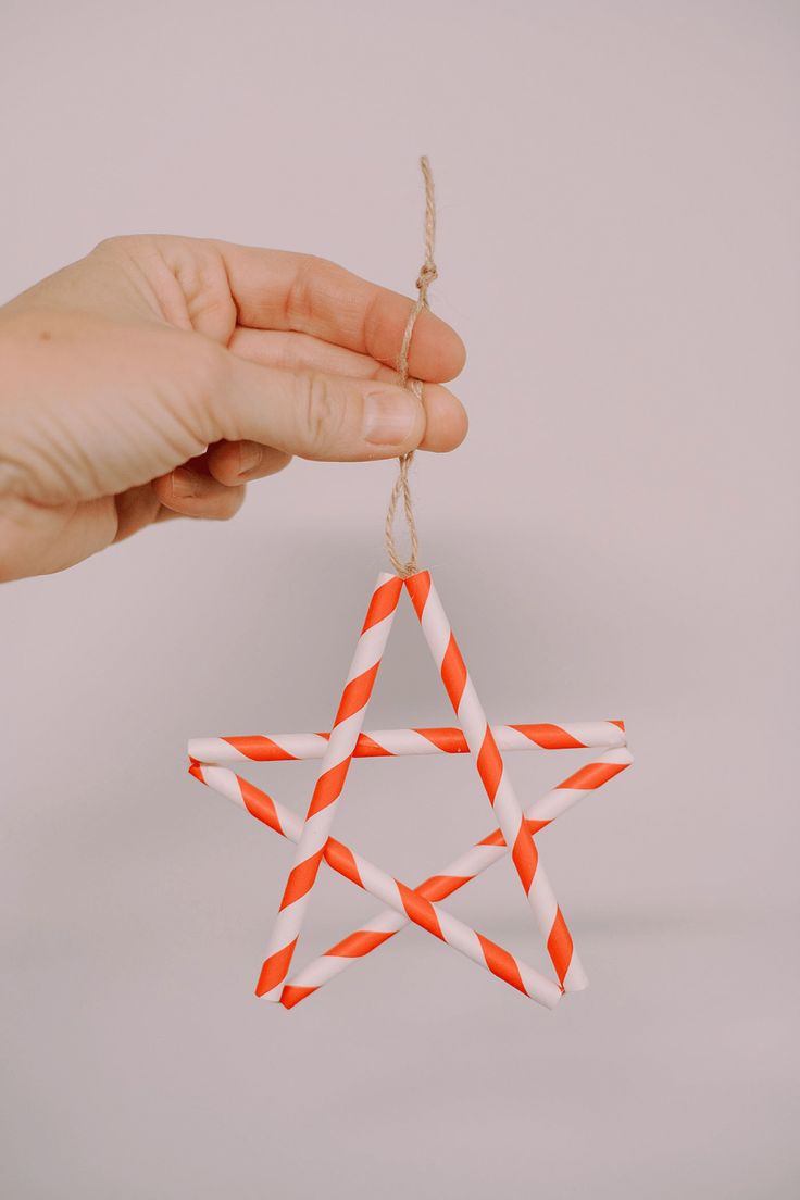 a hand is holding an ornament made out of paper straws that look like a star