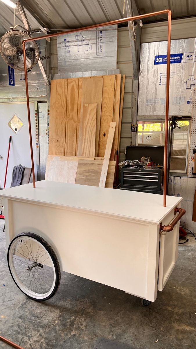 a white cart sitting inside of a garage next to some wooden boards and plywood