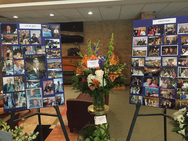 flowers and pictures are placed on easels in front of a wall full of photos