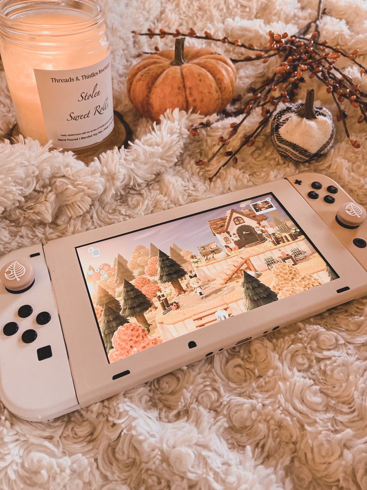 a nintendo wii game system sitting on top of a white blanket next to candles and pumpkins