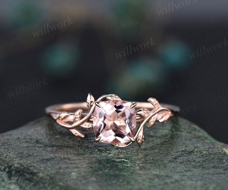 a pink morganite ring sitting on top of a rock