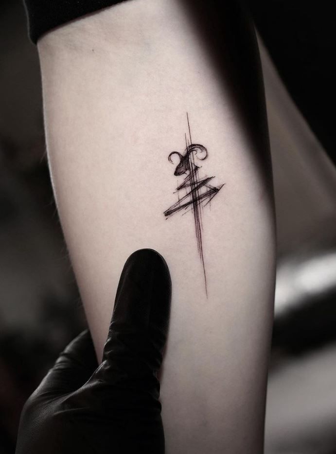 a person with a tattoo on their arm is holding up a small cross and arrow